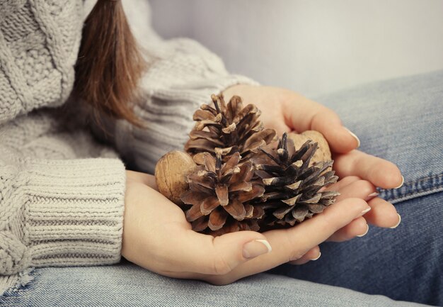 Quelques pommes de pin et noix dans les mains de la femme, gros plan