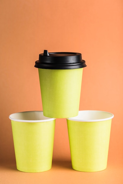 Quelques tasses à café réutilisables en papier vert avec un couvercle noir fermé.
