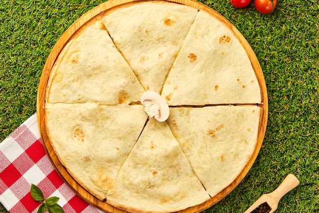 Quesadilla mexicaine au poulet, fromage et champignons sur l'herbe verte