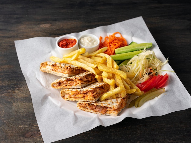 Photo quesadilla mexicaine avec poulet, concombres, tomates, cornichons et frites