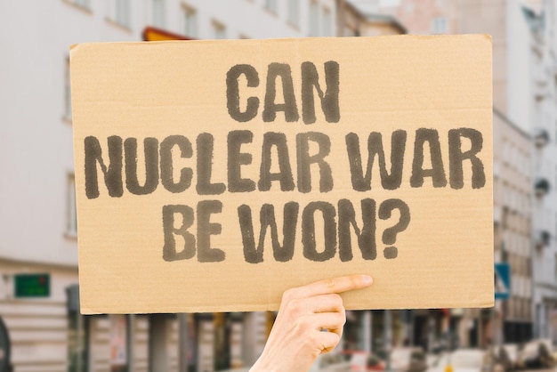 La question Peut-on gagner la guerre nucléaire est dessinée sur une bannière en carton dans les mains des hommes Catastrophe Apocalypse Survie Résilience Peur Panique Anxiété Tension Manifestation Manifestation Rallye Activiste
