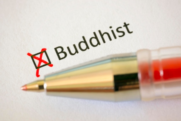 Photo questionnaire stylo rouge et l'inscription buddhist avec croix sur le papier blanc