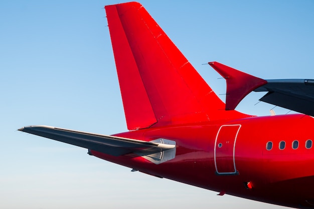 Queue et arrière de l'avion de passagers de couleur rouge contre le ciel bleu