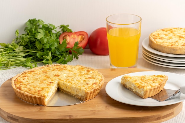 Quiche au fromage une tarte sur une planche de bois une tranche de tarte sur une assiette blanche