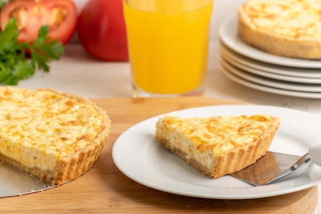 Quiche au fromage une tarte sur une planche de bois une tranche de tarte sur une assiette blanche