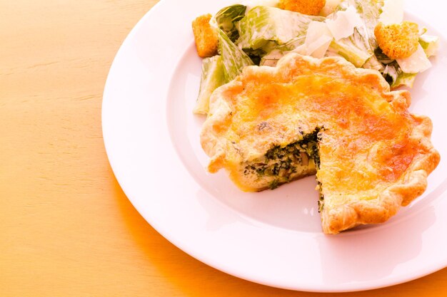 Quiche aux épinards individuelle servie avec salade.