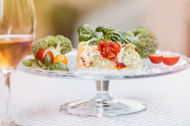 Quiche aux tomates, brocoli et fromage aux herbes sur un plateau en verre