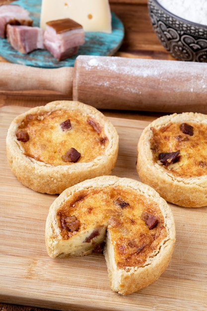 Quiche lorraine maison sur planche de bois avec des ingrédients.