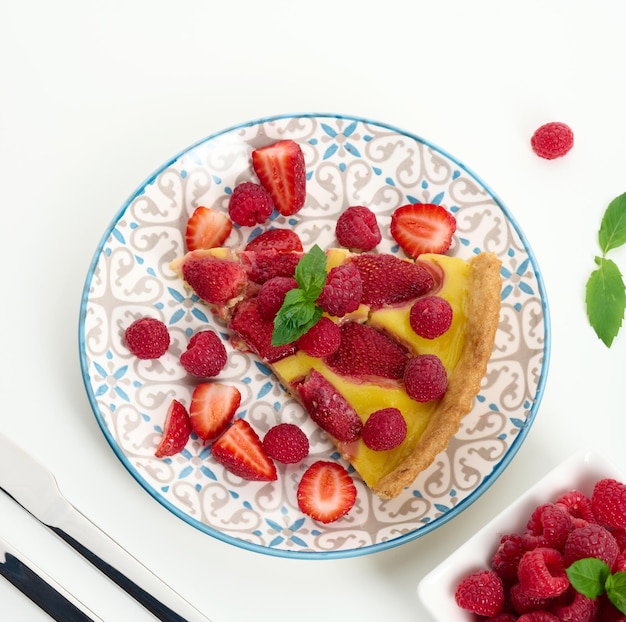 Quiche ronde aux fraises rouges et framboises sur un tableau blanc