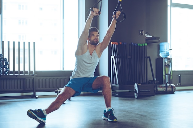 Équilibre et puissance. Pleine longueur de jeune homme en vêtements de sport s'exerçant au gymnase