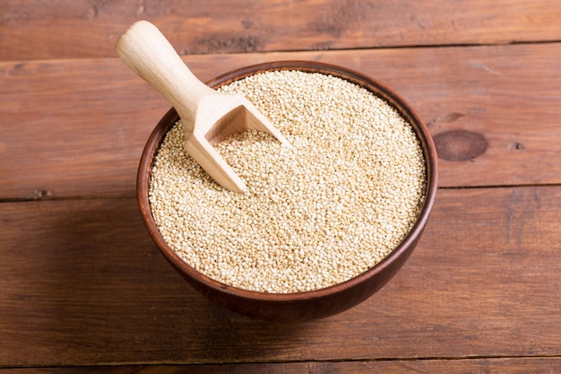 Quinoa blanc dans un bol sur fond de bois Superfood