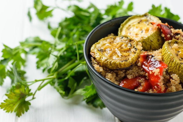 Quinoa bouilli, légumes cuits au four et herbes dans un bol sur la table