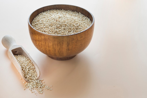 Quinoa cru avec une cuillère en bois sur fond marron