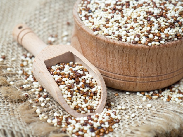 Quinoa dans un bol en bois et scoop sur fond rustique