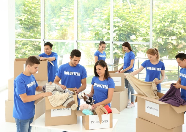 Équipe d'adolescents bénévoles recueillant des dons dans des boîtes en carton à l'intérieur