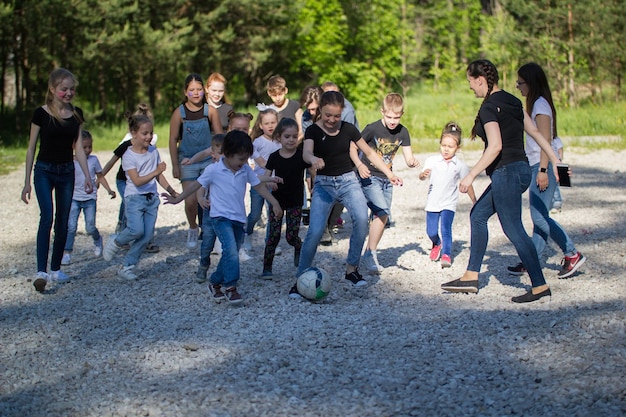Équipe d'adolescents jouant au football de cour avec une équipe d'enfants aux beaux jours