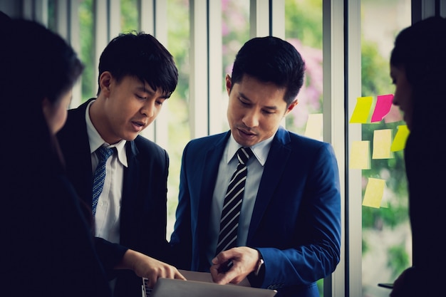 Équipe affaires asiatiques debout parler parler travail dans la salle de bureau