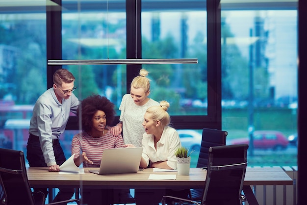 Équipe d'affaires multiethnique en démarrage lors d'une réunion dans un brainstorming intérieur de bureau de nuit moderne, travaillant sur un ordinateur portable