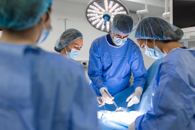 Équipe d'assistants chirurgiens professionnels et d'infirmières effectuant une chirurgie invasive sur un patient dans la salle d'opération de l'hôpital Les chirurgiens parlent et utilisent des instruments Un véritable hôpital moderne