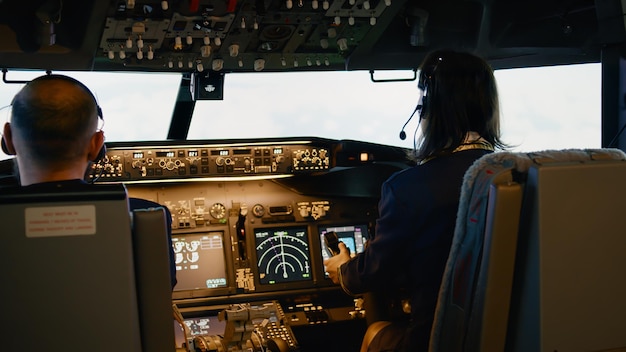 Équipe de capitaine et de femme copilote fixant l'altitude et la longitude pour piloter l'avion avec le tableau de bord du panneau de commande dans le cockpit. Moteur étranglé et décollage avec boussole de navigation.