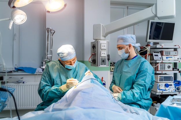 Équipe de chirurgiens opérant une personne Hommes en uniforme de protection dans une chambre d'hôpital moderne