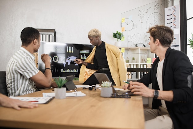 Équipe de commerçants masculins multiculturels ayant des négociations au bureau avec des gadgets modernes