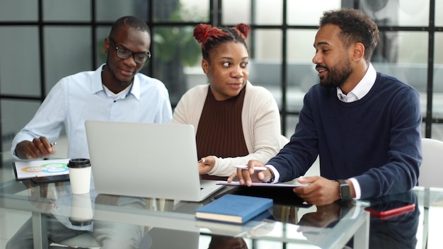 Équipe commerciale afro-américaine parlant de stratégie tout en regardant un ordinateur portable au bureau