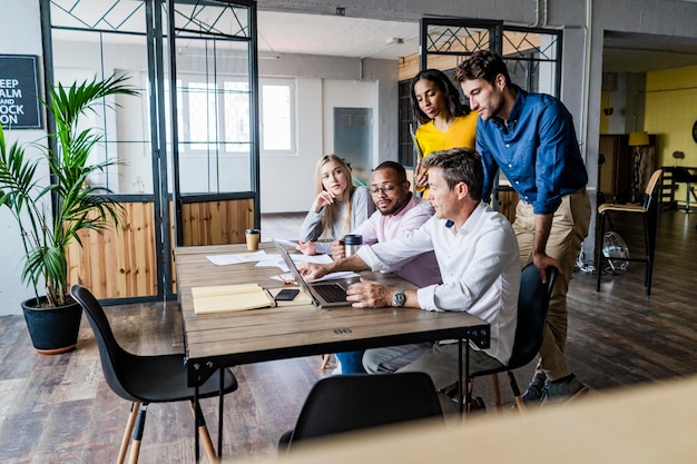 Équipe commerciale ayant une réunion dans un bureau loft regardant un ordinateur portable ensemble