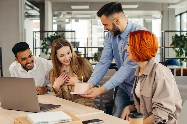 Équipe commerciale célébrant l'anniversaire d'un collègue avec un gâteau au bureau Célébrant l'anniversaire d'un employé sur le lieu de travail