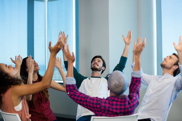 Équipe commerciale créative assise avec leurs bras au bureau