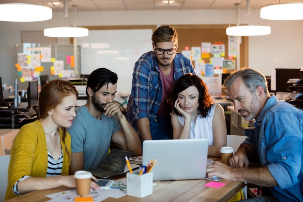 Équipe commerciale créative discutant sur l'ordinateur portable au bureau