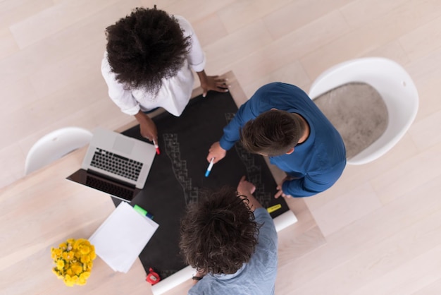 Équipe commerciale de démarrage multiethnique lors d'une réunion dans un brainstorming intérieur de bureau moderne et lumineux, vue de dessus