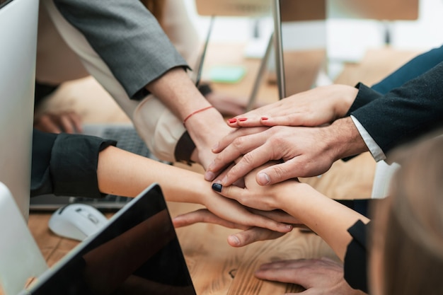 Équipe commerciale joignant leurs mains sur le bureau