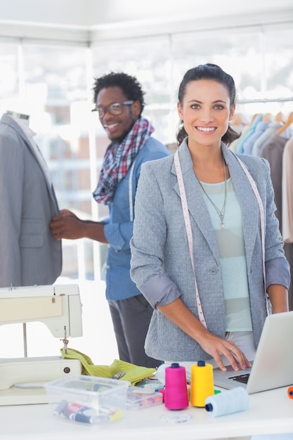 Équipe de créateurs de mode travaillant et souriant à la caméra