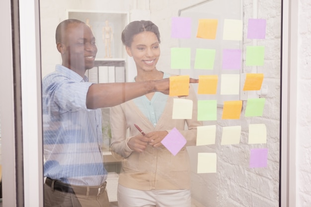 Équipe de création d&#39;entreprise pointant des notes adhésives