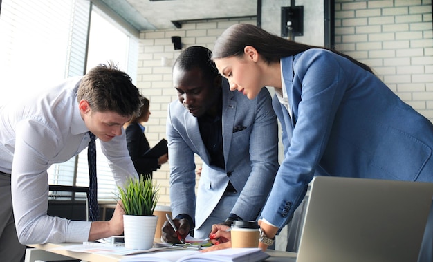 Équipe de démarrage d'entreprise lors d'une réunion dans un brainstorming intérieur de bureau moderne et lumineux, travaillant sur un ordinateur portable et une tablette.