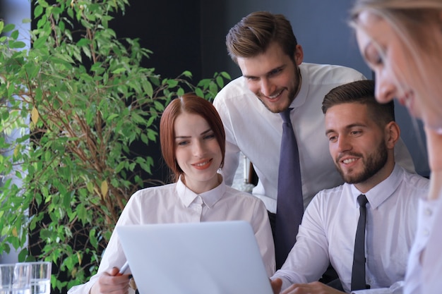 Équipe de démarrage d'entreprise lors d'une réunion dans un intérieur de bureau moderne et lumineux et travaillant sur un ordinateur portable.