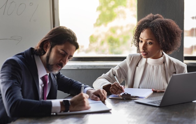 Équipe de direction multiethnique prenant des notes lors d'une réunion au bureau