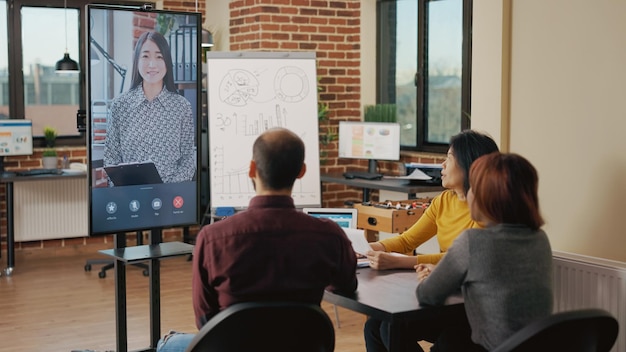 Équipe diversifiée assistant à une réunion d'affaires par vidéoconférence avec une femme pour parler de croissance et de partenariat. Collègues de démarrage travaillant en équipe avec une personne en téléconférence à distance.