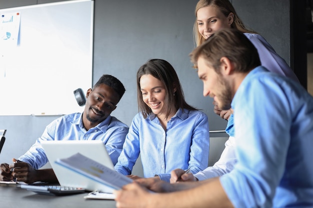 Équipe d'entreprise de démarrage lors d'une réunion dans un brainstorming intérieur de bureau moderne et lumineux, travaillant sur un ordinateur portable et une tablette