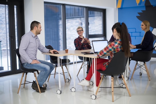 Équipe d'entreprise de démarrage lors d'une réunion dans un brainstorming intérieur de bureau moderne et lumineux, travaillant sur un ordinateur portable et une tablette