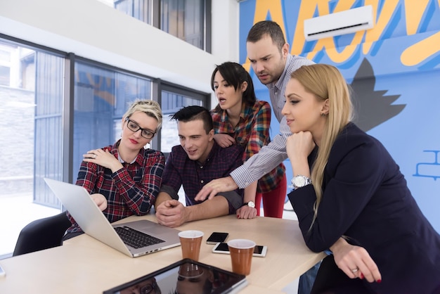 Équipe d'entreprise de démarrage lors d'une réunion dans un brainstorming intérieur de bureau moderne et lumineux, travaillant sur un ordinateur portable et une tablette