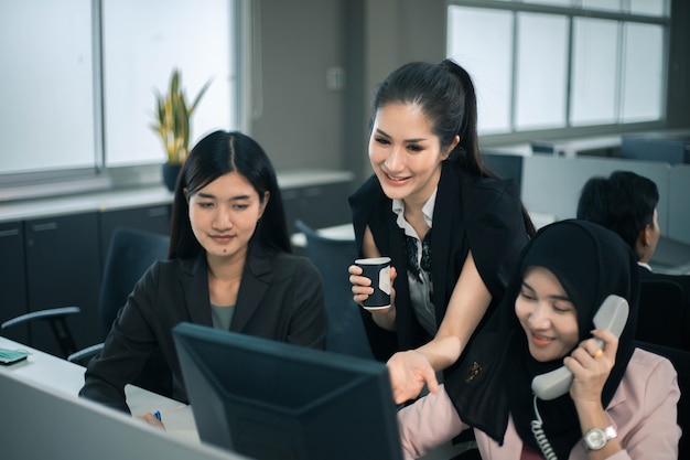 Équipe de femmes d'affaires souriantes travaillant au bureau et discutant d'un projet sur ordinateur