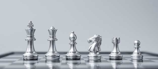 Équipe de figurines d'échecs d'argent (roi, reine, évêque, chevalier, tour et pion) sur l'échiquier contre l'adversaire pendant la bataille.