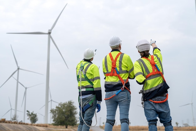 Équipe d'ingénieurs éoliens discutant de l'inspection et de l'entretien des éoliennes dans les parcs éoliens