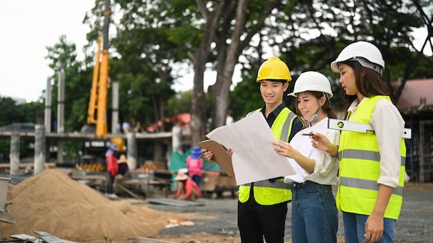 Équipe d'ingénieurs portant un casque et un gilet de sécurité inspectant le chantier de construction d'un bâtiment industriel Concept de construction d'ingénieur de l'industrie