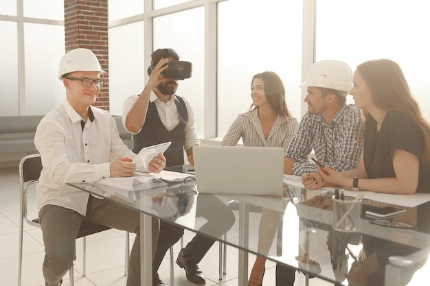 Équipe de jeunes designers professionnels discutant d'idées sur le plan directeur lors d'une table de réunion dans un studio moderne