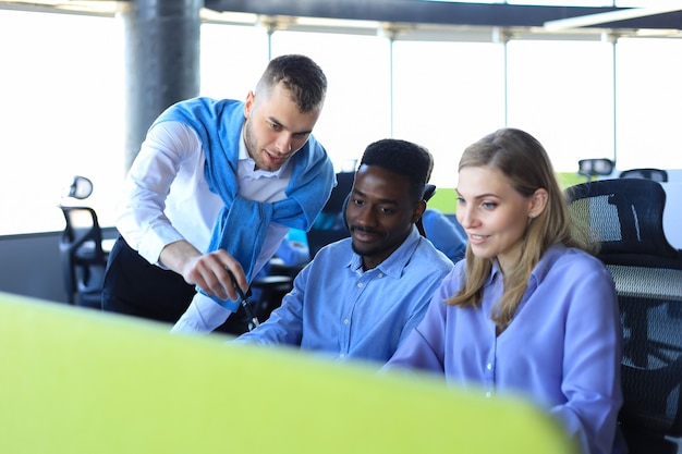 Équipe de jeunes professionnels ayant une discussion informelle au bureau. Cadres ayant une discussion amicale pendant la pause.