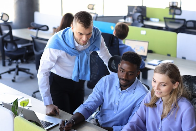 Équipe de jeunes professionnels ayant une discussion informelle au bureau. Cadres ayant une discussion amicale pendant la pause.