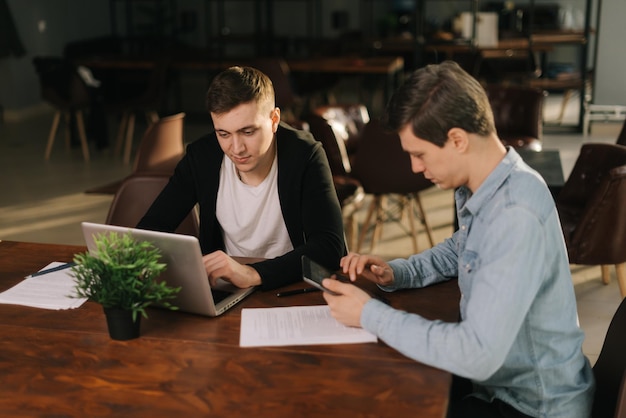 Équipe marketing de jeunes hommes d'affaires discutant du projet ensemble à la table avec un ordinateur portable lors d'une réunion de bureau. Concept de travail d'équipe des jeunes gens d'affaires.